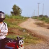 Șofer care verifică nivelul uleiului de motor cu joja, sub capota deschisă a mașinii
