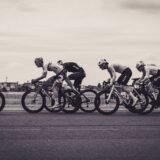 Grup de cicliști amatori care pedalează pe o șosea de țară, în timpul unei curse de lungă distanță