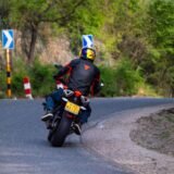 Motociclist echipat complet, cu cască integrală și geacă de protecție, pe un drum de țară